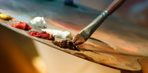 Vibrant artist palette with paint and brush creating colorful artwork.