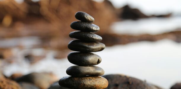 A stack of smooth stones artfully balanced by a waterside, evoking tranquility and zen.